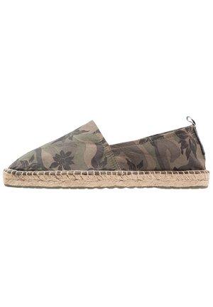 Grüne Camouflage-Espadrille mit einem Stoffoberteil, Jutesohle und gewebtem Rand. Das Design zeigt florale Muster vor einem strukturierten Hintergrund.