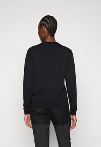 Felpa nera con collo rotondo, maniche lunghe e polsini e orlo a costine. Texture liscia, design minimale e senza loghi o motivi visibili.