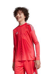 Rotes Longsleeve-Sporttrikot mit strukturiertem Design und Rundhalsausschnitt. Es hat graue Streifen an den Schultern und besteht aus atmungsaktivem Material.