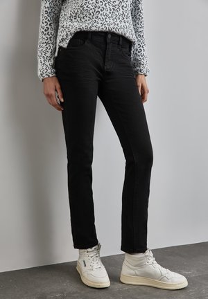 Černé, slim-fit džínsy vyrobené z denimu, s klasickým designem pěti kapes. Ve spojení s bílými vysokými teniskami a vzorovaným svetr.