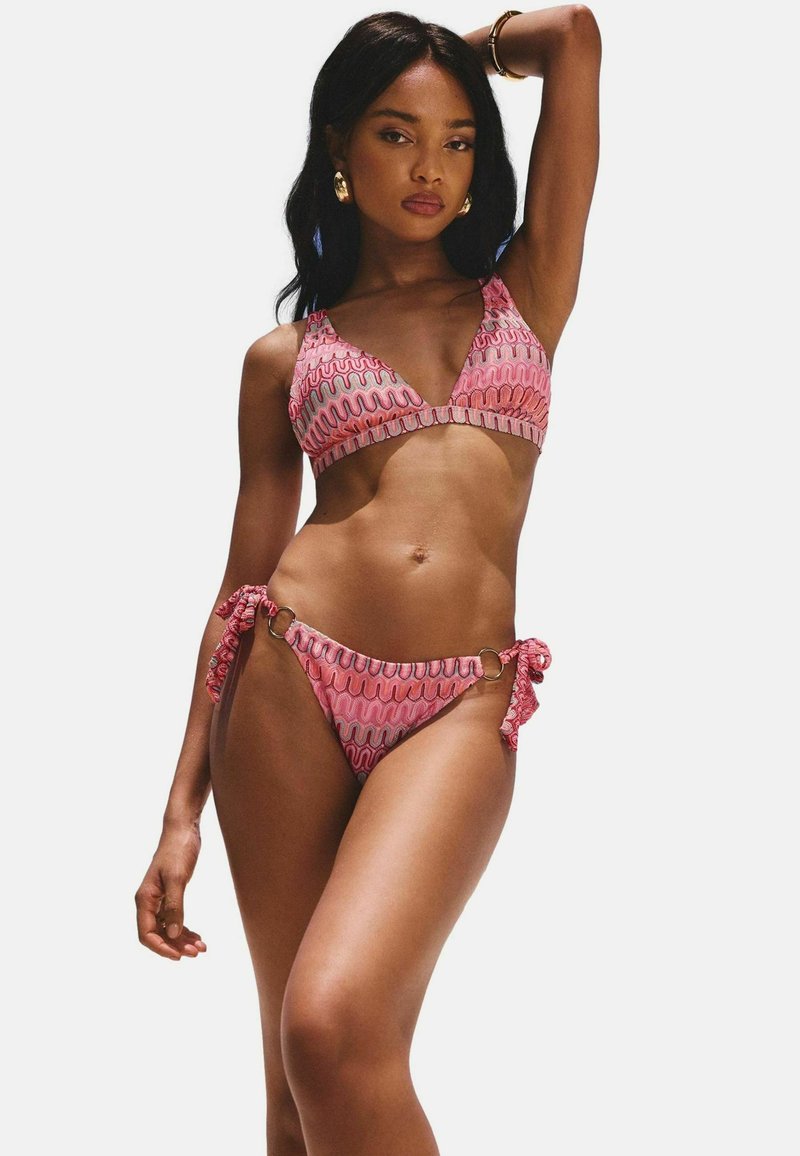 Roze bikini set met een golvend patroon, voorzien van een driehoekstop en onderkant met strik aan de zijkant, accentueert met ronde hardware. Gladde textuur.