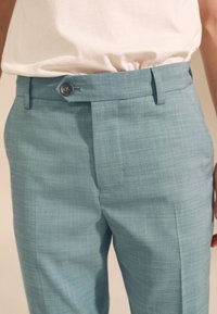 Hellblaue, maßgeschneiderte Hose aus strukturiertem Stoff mit Knopfverschluss, Gürtelschlaufen und flachem Frontdesign.