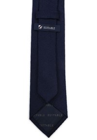Marineblauwe stropdas van een gestructureerde stof, met een smallere punt. Een klein label "SUITABLE" is zichtbaar nabij de bovenkant.