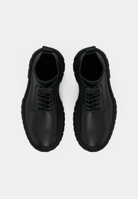 Μαύρες δερμάτινες μπότες με κορδόνια, στρογγυλή μύτη, ελαστική σόλα και επενδεδυμένος αστράγαλος. Διαθέτουν ανθεκτικά κορδόνια και λεία επιφάνεια.