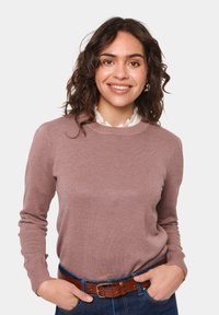 Ljust rosafärgad tröja i mjukt material med långa ärmar och rund halsringning. Matchad med ett brunt bälte över blå jeans.