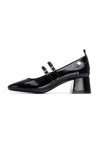 Zapatos de tacón de charol negro con punta afilada, dos correas ajustables, acentos de metal plateado y un tacón medio en bloque.