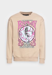 Felpa beige con una stampa grafica di uno scheletro all'interno di un design circolare, con accenti rosa e blu e il testo "IL TEMPO È UN'ILLUSIONE."