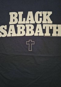 Zwart katoenen T-shirt met grote, vetgedrukte, witte tekst "BLACK SABBATH" en een klein kruis symbool eronder.