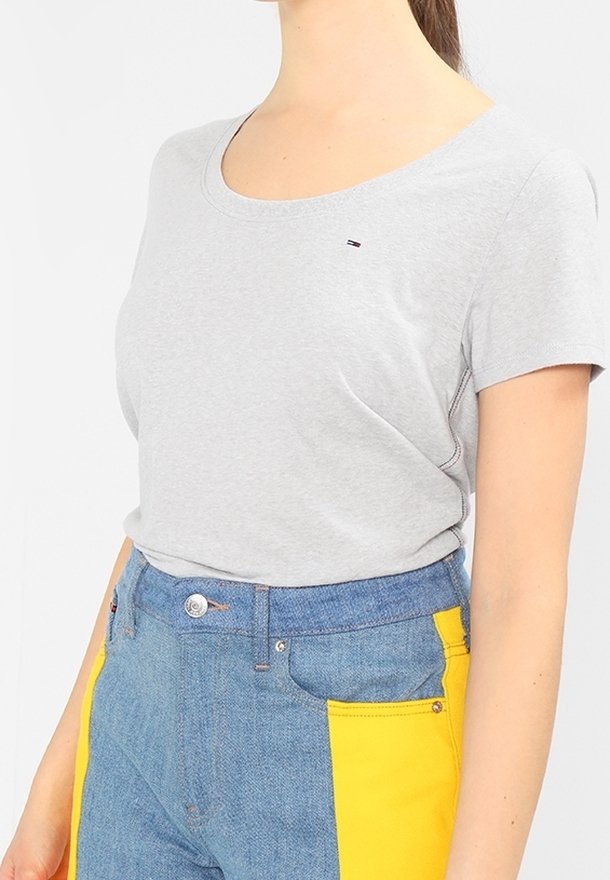 Gray cotton t-shirt with a scoop neckline and short sleeves, paired with high-waisted blue denim pants featuring yellow side pockets.