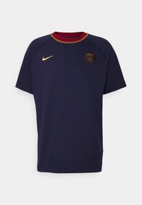 Camiseta de algodón azul marino con cuello redondo rojo, detalles dorados y un logo circular con "París" en el centro. Manga corta, corte relajado.