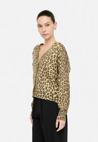 Cárdigan de estampado de leopardo en beige y marrón, con escote en V, mangas largas y un dobladillo ligeramente recortado. Fabricado en material de punto suave.