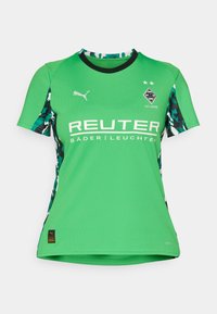 Roheline jalgpallipaita on valmistatud kergest kangast. Sellel on mustad ja teal värvi kamuflaažvarrukad, rinnal logo "REUTER" ja kaks tähte rinna kohal.