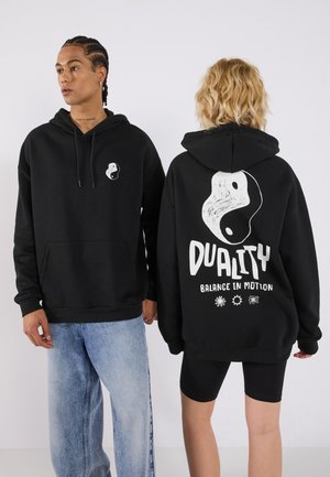 Black hooded sweatshirt featuring a front yin-yang logo and large "DUALITY" graphic with text on the back. Cotton blend, casual fit.