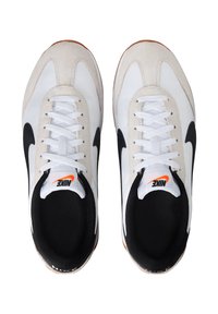 Sneakers Nike bianchi e neri con un accento in suede, caratterizzati da lacci bianchi, punta rotonda e suola in gomma con marchio arancione all'interno.