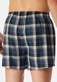 Blauwe en grijze geruite boxershort met een elastische tailleband en een lichtgewicht, gestructureerde stof. Kenmerkt zich door een checked patroon met verschillende strepen.