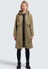 Giacca lunga verde oliva con cappuccio, zip frontale, vita elastica e due tasche laterali. Il materiale appare leggero e con una texture.