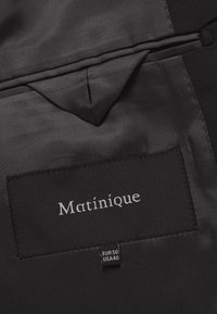 Black fabric interior featuring a stitched label with "Matinique" and size tags EUR 50, USA 40. Smooth texture with a subtle sheen.
