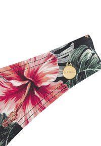 Ziedu raksta audums rozā un zaļā krāsā uz melna fona, ar zelta piederumiem, kuros redzams zīmola logo. Mīksta tekstūra un izliekta forma.