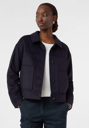 Navy wool blend cropped jacket with a collar, front pockets, and button closure. Features a textured white sweater underneath.