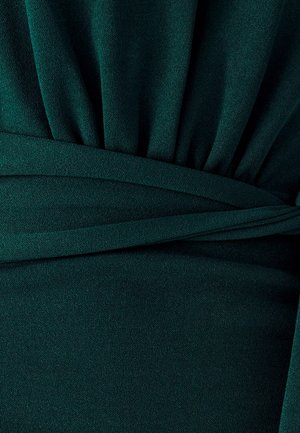 Vestido de tela verde con pliegues drapeados y cinturilla envolvente. La textura es suave con un acabado mate.