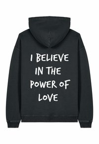 Felpa nera con cappuccio con testo bianco sul retro che recita "CREDO NEL POTERE DELL'AMORE." Materiale in misto cotone, taglio comodo.
