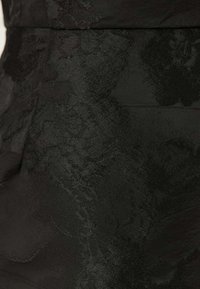 Tessuto nero con un motivo floreale testurizzato, finitura liscia e lucentezza sottile. Design sartoriale che enfatizza la forma e la struttura.