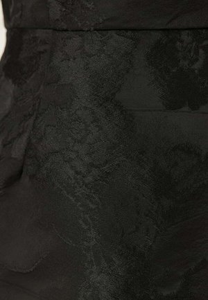 Sort stof med et tekstureret blomstermønster, glat finish og subtil glans. Skræddersyet design fremhæver form og struktur.