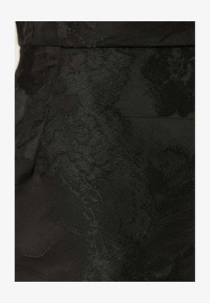 Sort stof med et tekstureret blomstermønster, glat finish og subtil glans. Skræddersyet design fremhæver form og struktur.