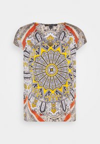 Haut à manches courtes, à motif circulaire en jaune, noir et blanc sur un fond beige, avec des accents rouges et un décolleté rond.