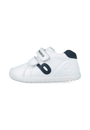 Zapatilla blanca con un upper de cuero texturizado, logo negro en el lateral, doble tira de Velcro y suela de goma para mayor agarre.