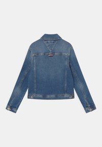 Džínová bunda středně modré barvy, s špičatým límcem, dlouhými rukávy a zapínáním na knoflíky na manžetách. Diskrétní zadní detailování s malou červenou a bílou cedulkou.