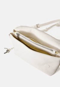 Borsa a tracolla bianca in pelle con superficie texturizzata. Presenta una fodera interna gialla e una chiusura con zip argentata. Design compatto e minimale.