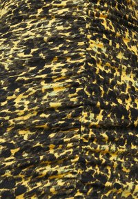 Tissu jaune et noir à motif, avec une surface texturée, présentant un design froissé et de subtiles variations de couleur et d'ombre.