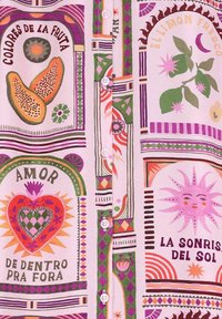 Chemise à manches courtes en tissu rose pâle, ornée de motifs fruits et floraux colorés, avec des bordures décoratives et des boutons blancs.