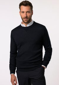 Marineblauer Strickpullover mit rundem Halsausschnitt, gerippten Bündchen und Saum sowie einem strukturierten V-förmigen Akzent auf der Brust. Trägt man über einem weißen Hemd mit Kragen.