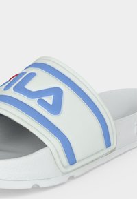Άσπρο σανδάλι slide με μπλε ρίγες και ανάγλυφο μπλε λογότυπο FILA στο λουράκι, με υφασμένο πέλμα και ανοιχτό σχέδιο δακτύλων.