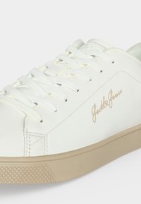 Λευκό sneaker χαμηλού τύπου με μπεζ σόλα και το λογότυπο "Jack & Jones" στη πλευρά, με λευκά κορδόνια και ραμμένες λεπτομέρειες.