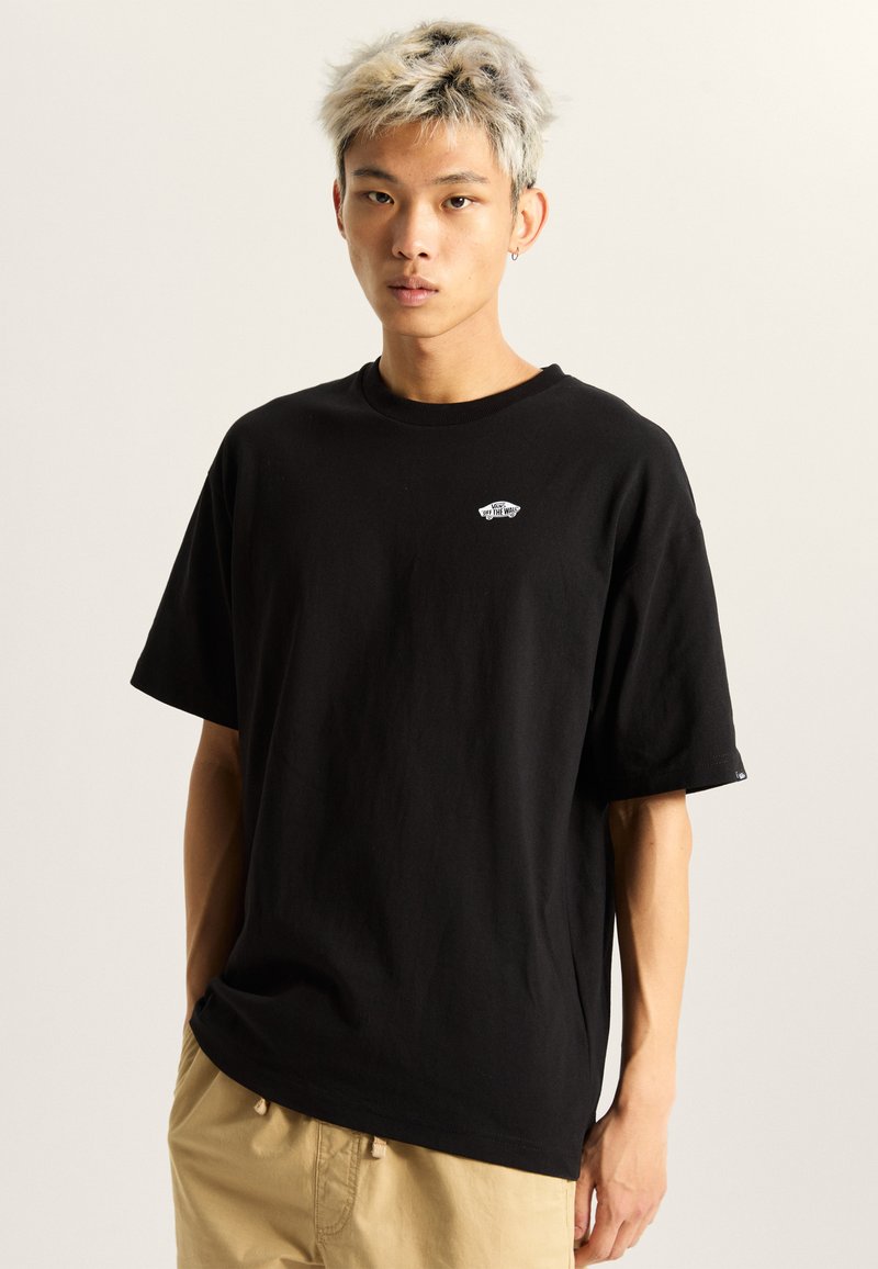 Camiseta de algodón negra con cuello redondo y mangas cortas, que presenta un pequeño logo blanco en el pecho. Corte relajado y textura suave.