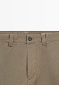 Spodnie khaki o gładkiej fakturze, z zapięciem na guzik, szlufkami na pasek oraz skośnym wzorem splotu.