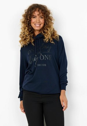 Sweat-shirt à capuche bleu marine avec une coupe décontractée, présentant un graphique frontal avec le texte "Un jour ou le jour un, vous décidez" en texte contrasté.
