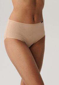 Beżowe majtki z wysokim stanem, wykonane z miękkiego materiału. Posiadają gładki, elastyczny krój z subtelną metką z logo na pasku.