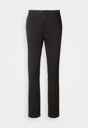 Zwarte op maat gemaakte broek met een rechte pijp, gemaakt van een soepele stof. Heeft een ritssluiting aan de voorkant en voorzakken.