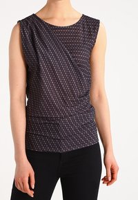 Marinblus utan ärmar med ett strukturerat mönster av små, ljusa blommor. Draperad design med rund halsringning och rynkad midja.