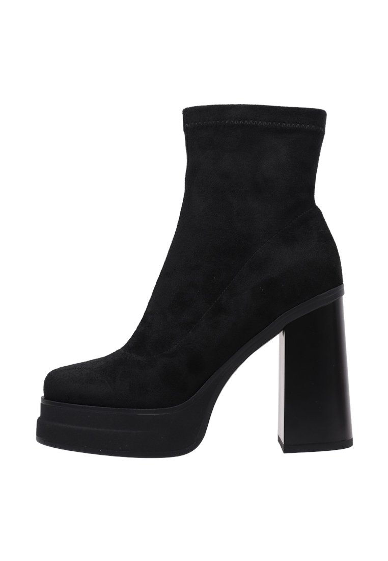 Botín de ante negro con un alto tacón de bloque, punta redondeada y parte superior elástica. Textura suave, diseño elegante y suela de plataforma para mayor altura.