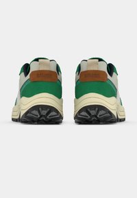 Roheline ja beež toss, millel on tekstureeritud pealne, kaunistatud pruuni nahast detailiga ja paksu musta kummist tallaga, mis on loodud hea haarduvuse tagamiseks.