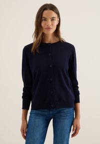 Navyblauwe gebreide cardigan met een ronde hals, lange mouwen en zes bijpassende knopen aan de voorkant. Gladde textuur en getailleerde stijl.