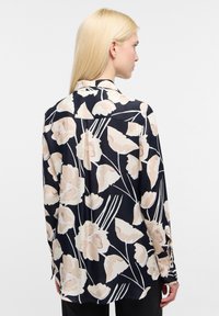 Chemise à manches longues navy avec un motif floral en beige clair. Fabriquée en tissu lisse, elle dispose d'un col classique et de poignets à boutons.