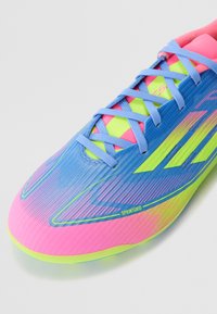 Sport shoes with a sleek design featuring a blue upper, pink accents, yellow details, and textured stripes, highlighting a performance fit.