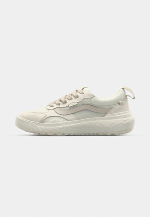 Beige treningssko med en teksturert overdel, glatte detaljer og en tykk, mønstret yttersåle. Har snøring og en løkke på hælen.