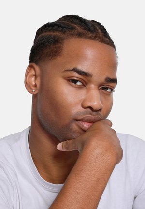 Headshot of a person with braided hair, smooth skin, a subtle earring, and a thoughtful expression, wearing a plain white T-shirt.